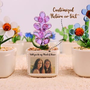 May include: Glass flower arrangements in white square pots. One arrangement features a purple flower, and another has a blue flower. The pots have a photo with the text "Will you be my Maid of Honor". The image also includes the text "Customized Picture or text".