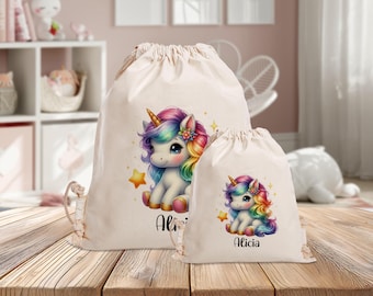 Könnte beinhalten: Zwei weiße Stoffbeutel mit Kordelzug und einem Einhorn-Motiv. Der größere Beutel hat den Namen "Alicia" aufgedruckt. Der kleinere Beutel hat den Namen "Alicia" aufgedruckt.