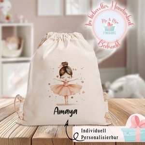 Puede incluir: Una bolsa de cord&oacute;n blanco con una ilustraci&oacute;n de bailarina rosa y el nombre "Amaya" impreso en ella. La bolsa est&aacute; personalizada con el texto "Personalizable individualmente".
