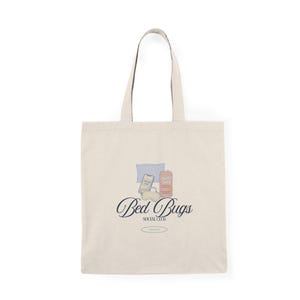 May include: A cream-coloured tote bag with black handles. The bag displays a graphic of a pillow, phone, and drink can. The words "Bed Bugs Social Club" are written in a script font.