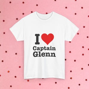 May include: White t-shirt with a red heart and the text "I love Captain Glenn" printed on the front.