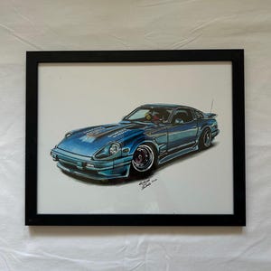 May include: A framed artwork featuring a blue sports car illustration. The car has a sleek design with black accents, a spoiler, and custom wheels. The artwork is framed in a black rectangular frame, and the background is white.