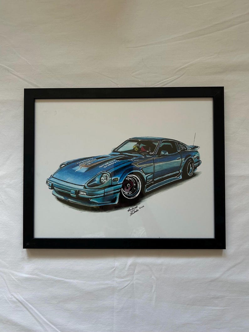 May include: A framed artwork featuring a blue sports car illustration. The car has a sleek design with black accents, a spoiler, and custom wheels. The artwork is framed in a black rectangular frame, and the background is white.