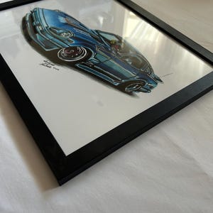 May include: Framed artwork featuring a blue sports car illustration. The car is depicted in a dynamic, angled perspective, with detailed shading and highlights. The artwork is encased in a black frame, adding a modern touch to the automotive art.