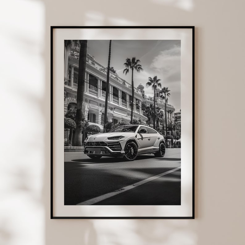 May include: A black and white photograph of a white Lamborghini Urus SUV parked on a street in front of a building with palm trees.