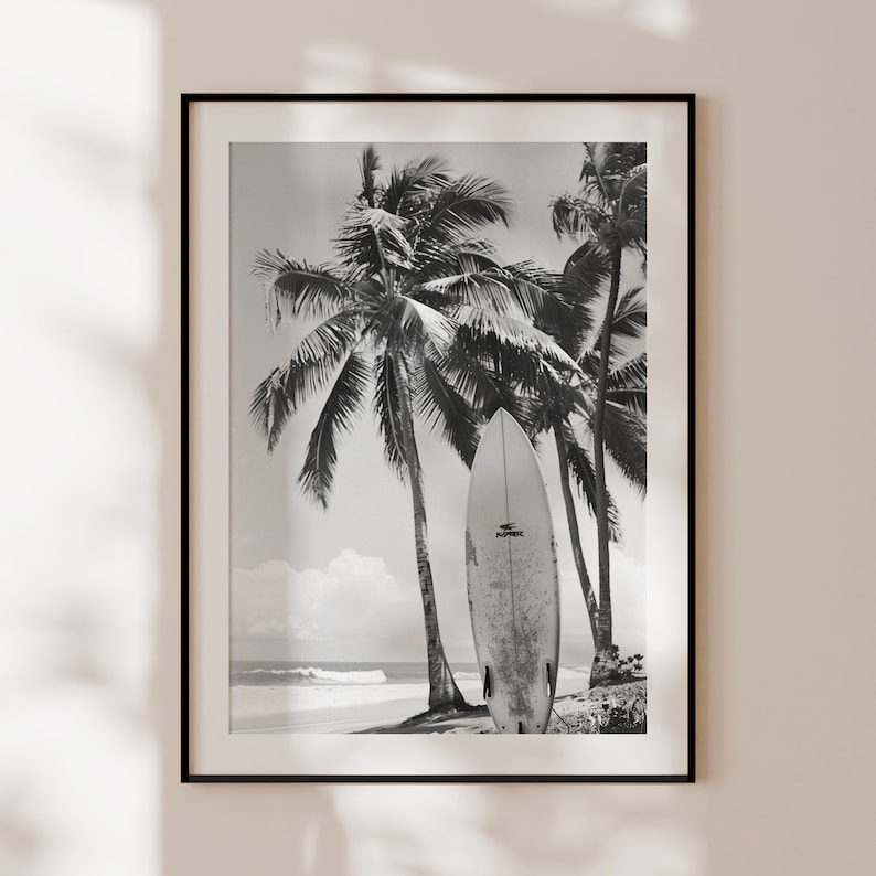May include: Black and white photograph of a surfboard leaning against palm trees on a beach. The surfboard has the word "Ripcurl" printed on it.