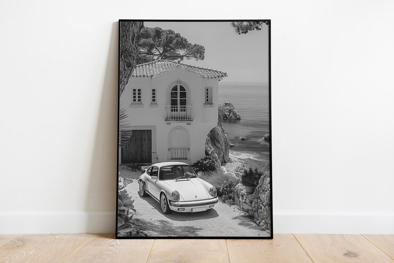 K&ouml;nnte beinhalten: Ein Schwarzwei&szlig;foto eines wei&szlig;en Porsche 911, der vor einem wei&szlig;en Haus mit Blick auf das Meer geparkt ist.