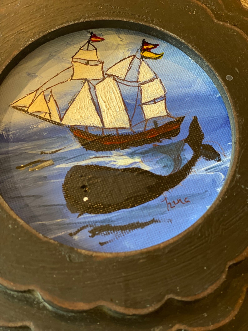 K&ouml;nnte beinhalten: Ein gerahmtes Gem&auml;lde mit einem Segelboot mit wei&szlig;en Segeln und einem schwarzen Wal, der darunter schwimmt. Das Gem&auml;lde hat einen blauen Hintergrund und ist unten rechts mit "Hena" signiert.