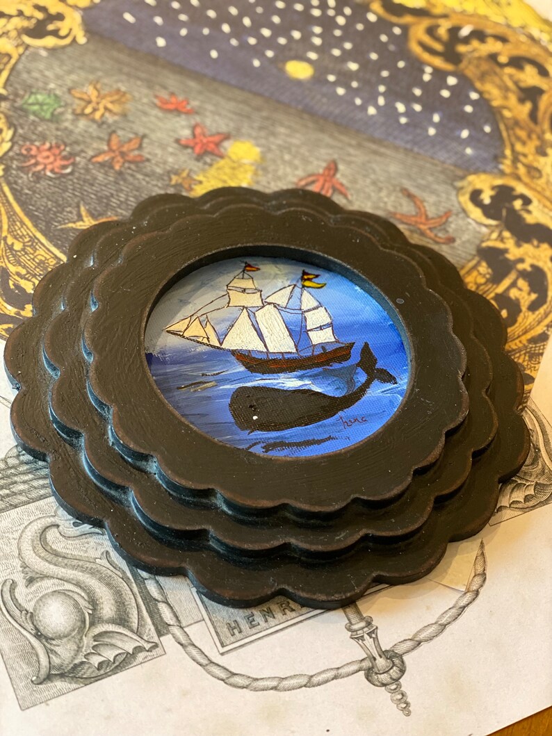 K&ouml;nnte beinhalten: Ein gerahmtes Gem&auml;lde, das ein Schiff zeigt, das auf einem blauen Meer segelt, unter dem eine Wal schwimmt. Das Gem&auml;lde ist vor einem sternenklaren Nachthimmel mit einem gelben Mond platziert.