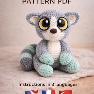 May include: A crocheted lemur pattern PDF. The lemur is gray, white, and mint green with large, expressive eyes. The text at the top reads "CROCHET LEMUR PATTERN PDF". The image also includes the text "Instructions in 3 languages:" with flags.