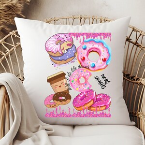 May include: White throw pillow with a colorful donut design. The design includes various donuts with pink, purple, and blue frosting, sprinkles, and the text "We like donuts" and "More donuts".