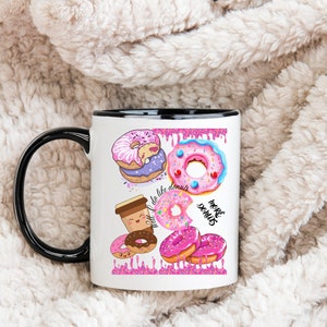 May include: White ceramic mug with a black handle and rim, featuring colorful donut illustrations. The design includes various donuts with pink frosting, sprinkles, and the text "do life donuts" and "more donuts".