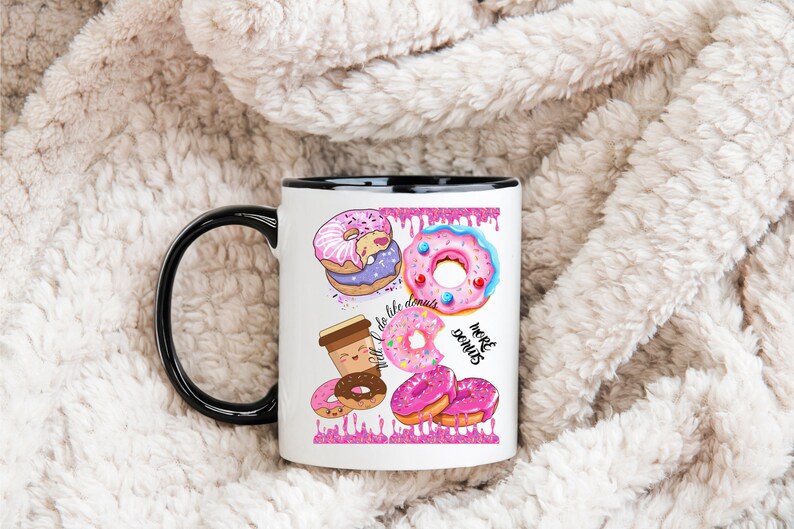 May include: White ceramic mug with a black handle and rim, featuring colorful donut illustrations. The design includes various donuts with pink frosting, sprinkles, and the text "do life donuts" and "more donuts".
