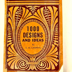 May include: Vintage book cover with the title "1000 Designs and Ideas" in a circular design. The cover is a warm orange color with dark brown decorative elements. The author's name, D. M. Campana, is also visible.