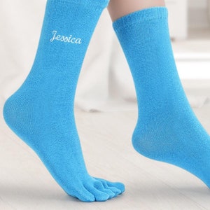 Puede incluir: Un par de calcetines de dedos de color azul claro con el nombre "Jessica" bordado en un calcetín.