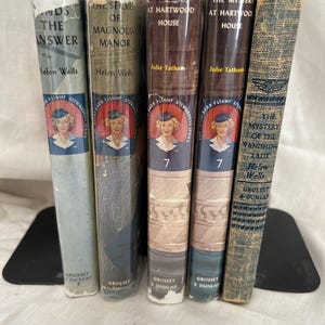 May include: Five vintage hardcover books from the Vicki Barr Flight Stewardess series, including titles like The Mystery at Hartwood House and The Mystery of the Vanishing Lady, featuring illustrated spines with portraits of a flight attendant.