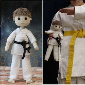 Könnte beinhalten: Zwei gehäkelte Puppen, die weiße Karate-Uniformen mit schwarzen Gürteln tragen. Die größere Puppe steht auf einer Ziegelstein-Oberfläche. Die kleinere Puppe wird von einer Person gehalten, die eine weiße Karate-Uniform mit einem gelben Gürtel trägt.