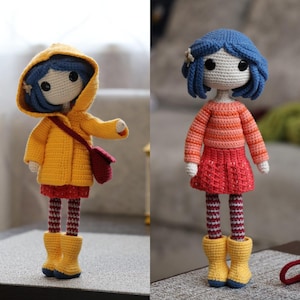 May include: Two crocheted dolls with blue hair, one wearing a yellow raincoat and the other wearing a red and orange striped sweater and a red skirt.
