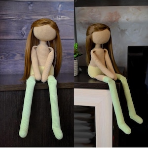Peut inclure: Poupée au crochet faite à la main avec de longs cheveux bruns et un visage vierge. Le corps de la poupée est beige, avec un short jaune et des jambes vert clair. La poupée est assise sur une surface marron foncé.