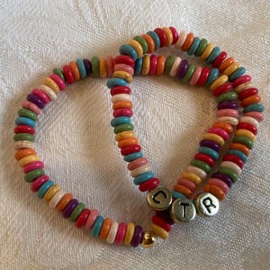 May include: Two colorful beaded bracelets with a variety of colors including red, orange, yellow, green, blue, and pink. The bracelets have the letters "CTR" on them. A gold-colored bead is at the end of one bracelet.