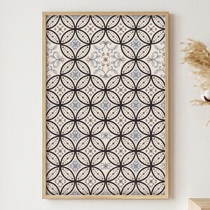 May include: A rectangular wall art print in a light wood frame featuring a repeating geometric pattern of interlocking black circles on a cream background, with small blue and tan floral motifs centered within each circular intersection.
