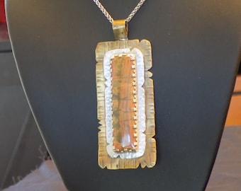 May include: A silver chain necklace with a rectangular pendant featuring a brown and white agate stone set in a brass frame.