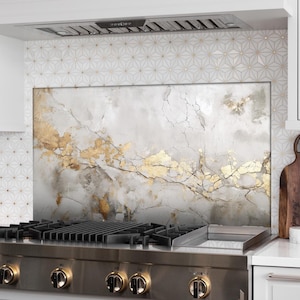 Op de afbeelding: Decoratieve keukenachterwand met een marmerachtig ontwerp met bladgoud accenten. De achterwand is geïnstalleerd achter een roestvrijstalen gasfornuis en voegt een vleugje elegantie toe aan de keuken.