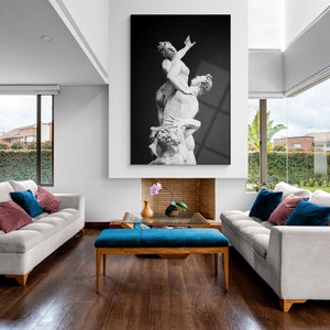 Pu&ograve; includere: Un soggiorno con due divani bianchi, un pouf blu e una fotografia in bianco e nero di una scultura appesa sopra un camino.