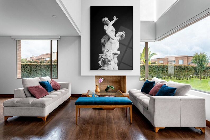 Pu&ograve; includere: Un soggiorno con due divani bianchi, un pouf blu e una fotografia in bianco e nero di una scultura appesa sopra un camino.