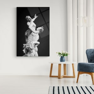 Pu&ograve; includere: Fotografia in bianco e nero di una scultura di tre figure, due uomini e una donna, in una posa drammatica.