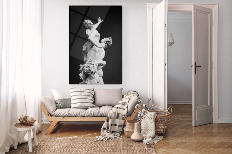 Pu&ograve; includere: Una fotografia in bianco e nero di una scultura che rappresenta tre figure in una posa drammatica. La scultura &egrave; esposta su una parete in un ambiente di soggiorno moderno.