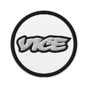 May include: A white circle with a black outline and the word "VICE" in a stylized, silver-colored font.