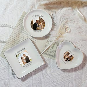 May include: Three white ceramic ring dishes in round, square, and heart shapes. Each dish features a wedding photo and text. The round dish has the text "One Wedding Day" and "MR & MRS WILSON 3rd August 2024". The square dish has the text "MR & MRS TAYLOR 17th May 2016".