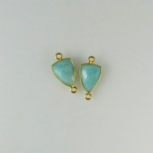 May include: Two gold-plated pendant connectors with a light blue gemstone in the shape of a triangle.