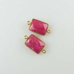 May include: Two gold-toned rectangular connector charms with pink gemstone inlays. The charms have a smooth, polished finish and are perfect for adding a touch of elegance to jewellery projects.