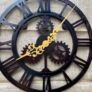 May include: A large, black, metal clock with Roman numeral markings and gold gears. The clock hands are gold and point to the time of 4:00.