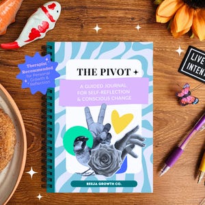 May include: A spiral-bound journal titled "The Pivot" with a blue and white cover, featuring a collage of images. The journal is accompanied by pens, decorative butterflies, and a patch that reads "Live With Intention". A donut and fish figurines are also present.