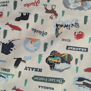 Peut inclure: Tissu crème avec un imprimé sur le thème de l'Alaska. Le motif comprend des illustrations d'ours, d'orignaux, de poissons et une carte de l'Alaska, ainsi que du texte tel que "Alaska", "Wasilla" et "The Last Frontier".