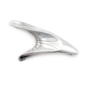 Puede incluir: Broche plateado de diseño abstracto y curvo. Presenta una forma similar a un ala, con detalles lineales grabados en un lado. El metal pulido refleja la luz, creando un efecto visual atractivo. Un accesorio elegante y moderno.