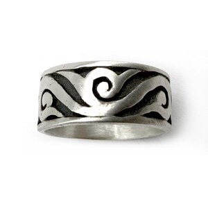 May include: A wide silver band ring featuring a continuous, raised, polished silver wave or scroll pattern set against a recessed, darkened, oxidized background that highlights the intricate, flowing, and swirling design elements.