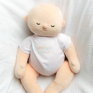 White toned realistically weighted baby doll with jointed limbs and a jointed head. The doll is 16" long, which is big enough to fit in preemie and some newborn clothing sizes, and weighs about 4 pounds. The doll has a soft filling similar to a stuffed animal and is weighted with quality glass beads. It is wearing a white onesie with the brand name, "Comfort Cuties."