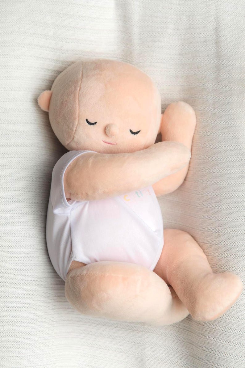 White toned realistically weighted baby doll with jointed limbs and a jointed head. The doll is 16" long, which is big enough to fit in preemie and some newborn clothing sizes, and weighs about 4 pounds. The doll has a soft filling similar to a stuffed animal and is weighted with quality glass beads. It is wearing a white onesie with the brand name, "Comfort Cuties."