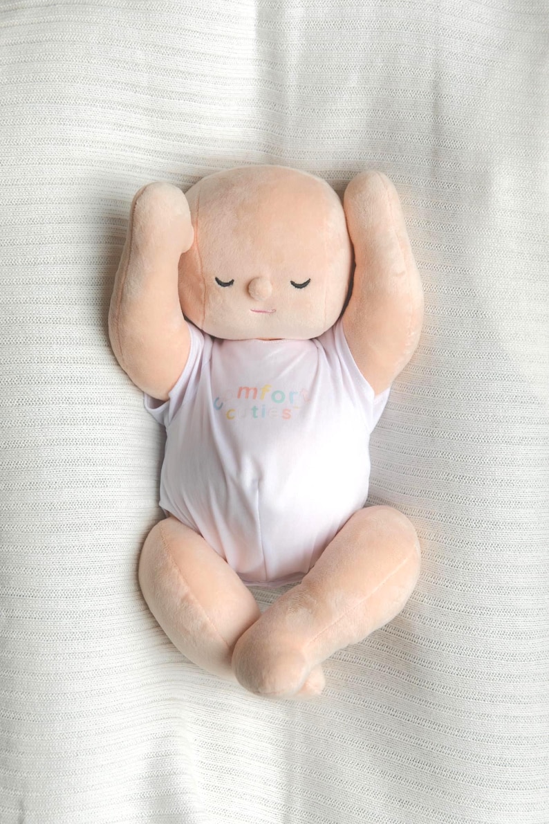 White toned realistically weighted baby doll with jointed limbs and a jointed head. The doll is 16" long, which is big enough to fit in preemie and some newborn clothing sizes, and weighs about 4 pounds. The doll has a soft filling similar to a stuffed animal and is weighted with quality glass beads. It is wearing a white onesie with the brand name, "Comfort Cuties."
