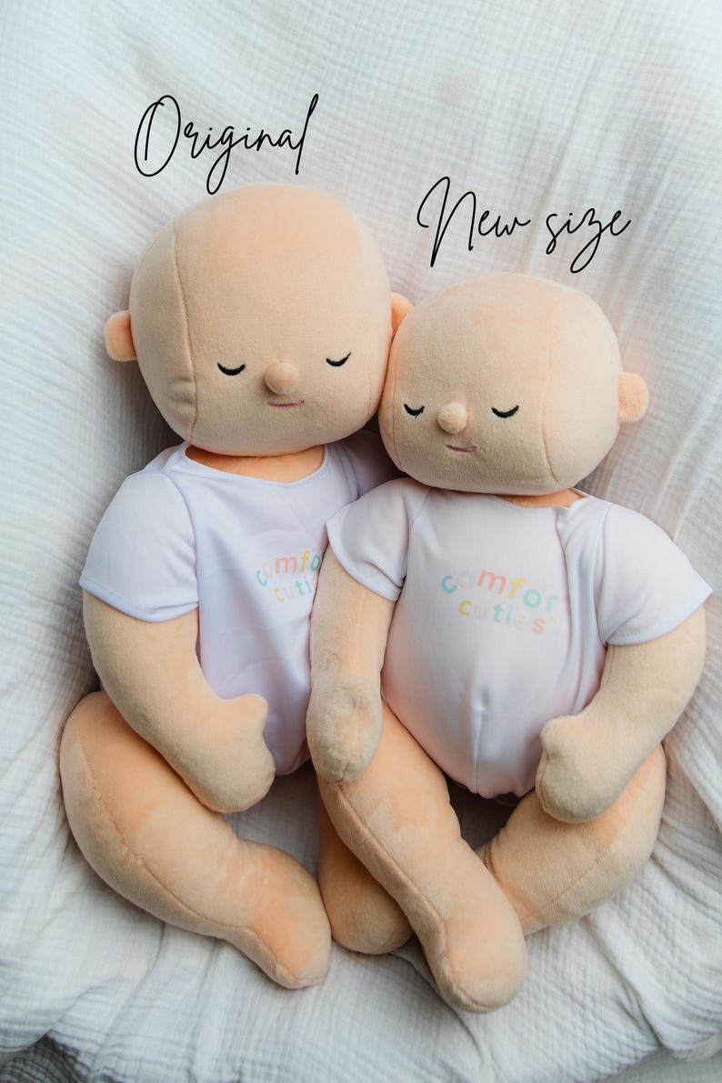 Puede incluir: Dos mu&ntilde;ecos de peluche con piel color melocot&oacute;n y ojos cerrados, que visten camisetas blancas con el texto "comfort cuties" en colores pastel. Los mu&ntilde;ecos est&aacute;n sentados sobre una superficie blanca y texturizada. Los textos "Original" y "New size" est&aacute;n escritos encima de los mu&ntilde;ecos.