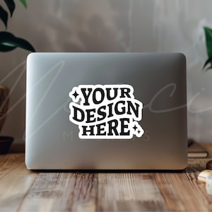 May include: A silver laptop computer with a white sticker that says "YOUR DESIGN HERE" with a star on either side of the text.