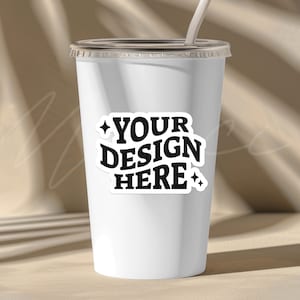 May include: White to-go cup with a black sticker that says "YOUR DESIGN HERE" with stars on either side.