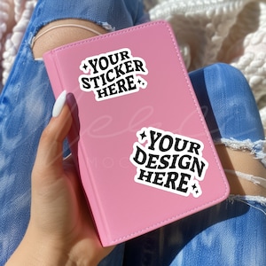 May include: A pink notebook with two white stickers. The stickers have black text that says "Your Sticker Here" and "Your Design Here".