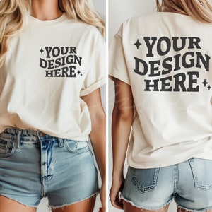 以下が含まれることがあります： 前面と背面に「YOUR DESIGN HERE」という文字がプリントされた白いTシャツ。デニムのショートパンツを履いた人が着用しています。