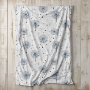 May include: White fabric with a repeating pattern of gray watercolor dandelions. The fabric is folded in the middle and has a slightly wrinkled texture.