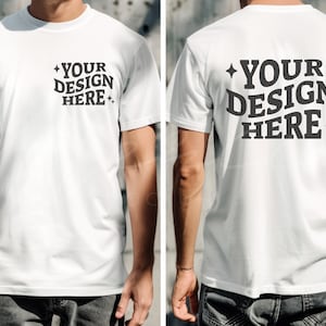 Può includere: Una t-shirt bianca a maniche corte e collo rotondo. La parte anteriore della t-shirt ha il testo "YOUR DESIGN HERE" stampato in nero. La parte posteriore della t-shirt ha lo stesso testo stampato in nero.